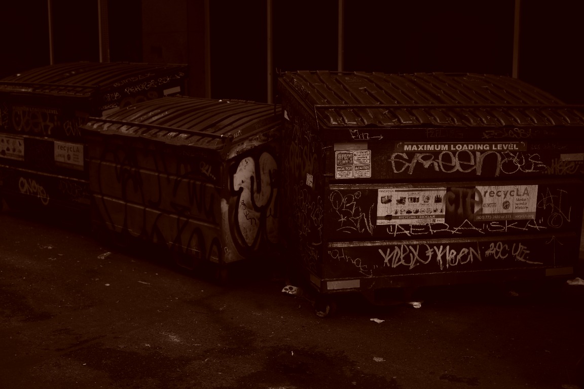 Sepia-toned alley dumpsters covered in graffiti