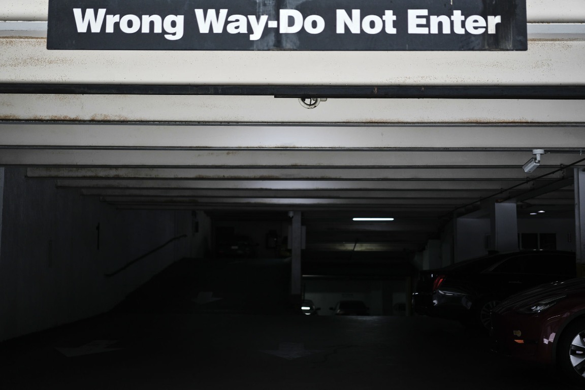 Wrong way sign over a dark parking garage entrance