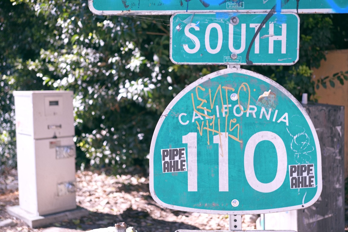 Green street sign layered with graffiti