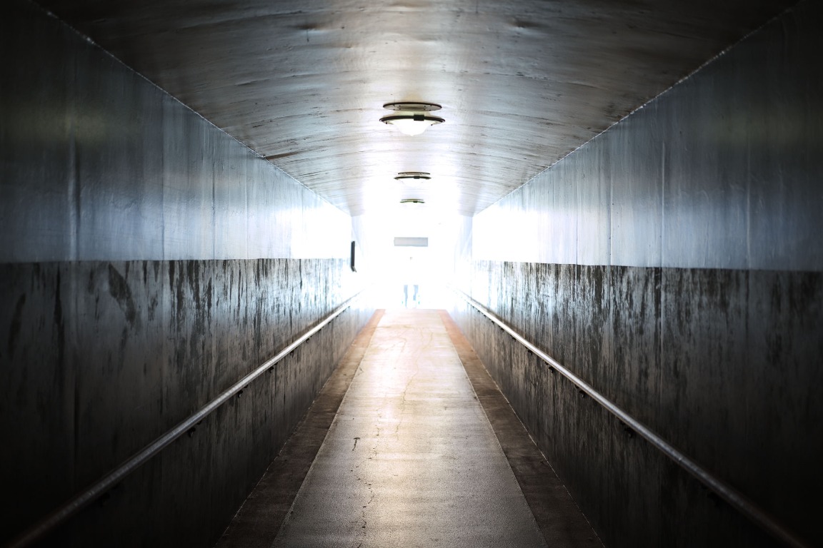 Concrete pedestrian tunnel opening into bright light