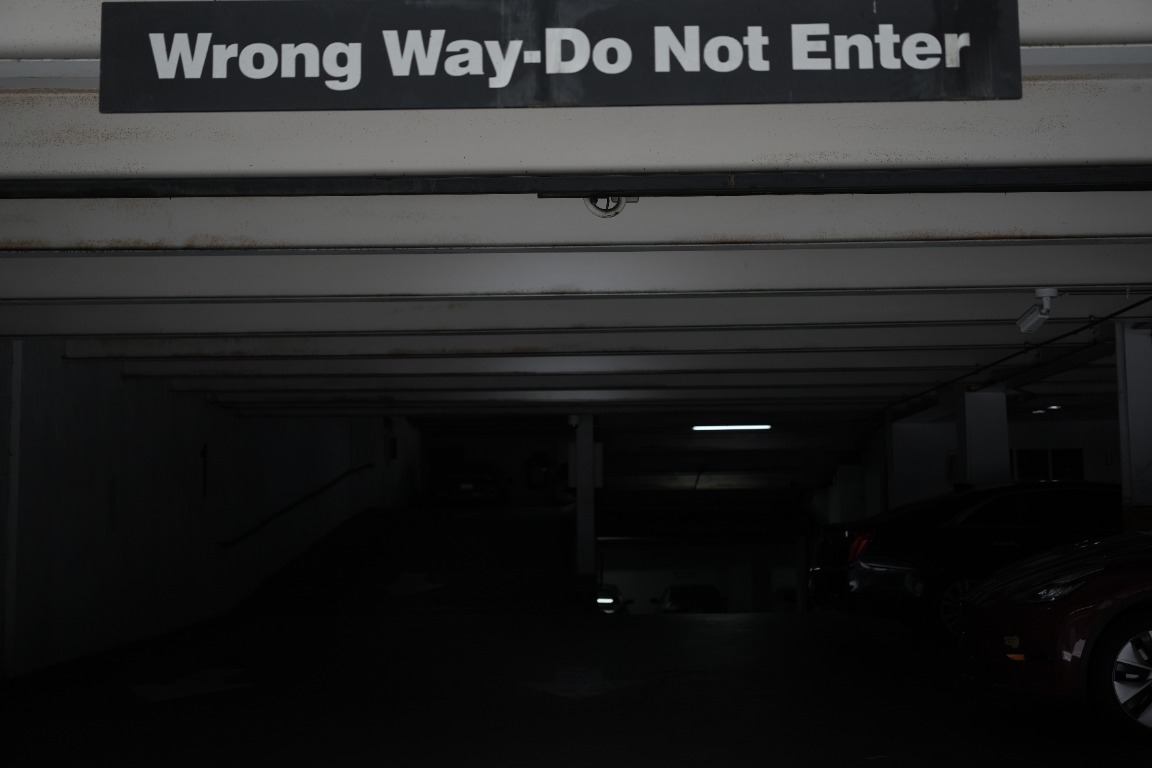 Wrong way sign above a dark parking garage entrance